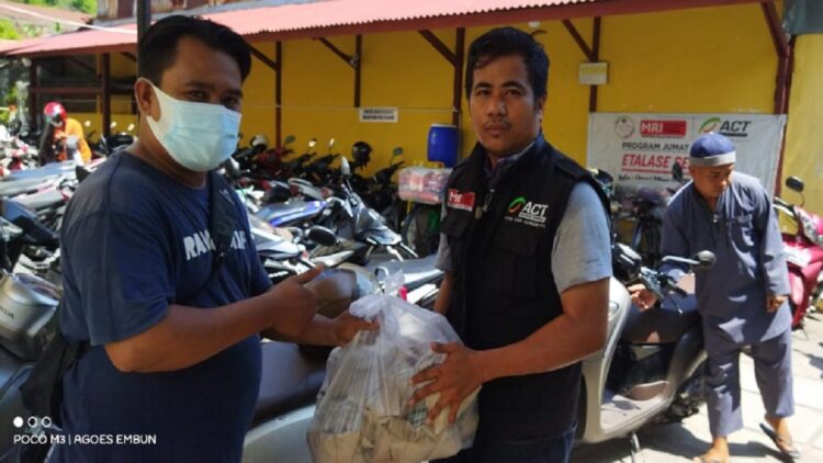 Salah seorang volunteer Komunitas Berbagi Nasi Jumat Berkah menyerahkan paket nasi ke Masjid Pasa Gadang.