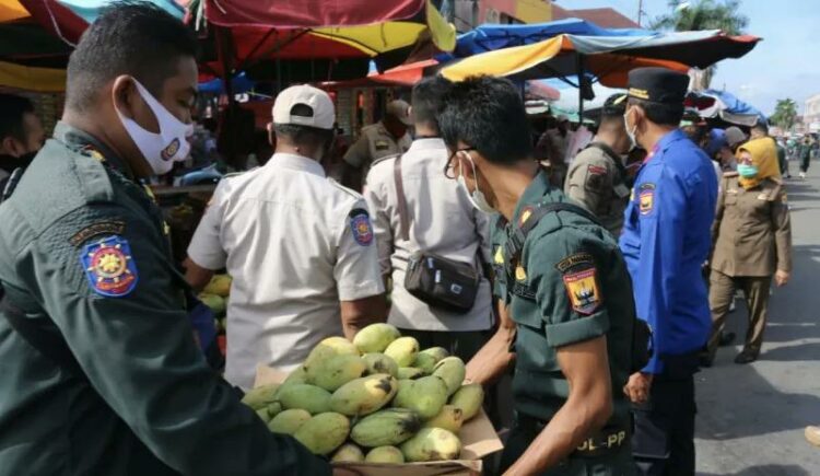 Satuan Polisi Pamong Praja dan Pemadam Kebakaran (Satpol PP dan Damkar) Kota Pariaman, Sumbar mengangkat meja pedagang buah di depan Pasar Rakyat Pariaman.