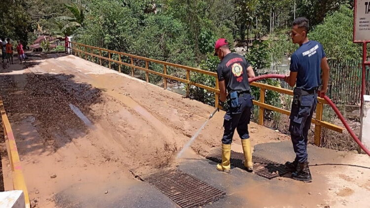 Petugas Damkar Padang membersihkan material longsor yang masih menutupi badan jalan di Sungai Pisang. (IST)