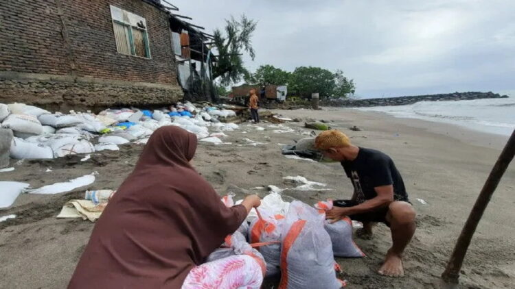 Warga Pasie Baru, Nagari Pilubang, Kecamatan Sungai Limau, Kabupaten Padang Pariaman, Sumbar sedang mengikat karung yang berisi pasir untuk membantu menahan ombak, Kamis. ANTARA/Aadiaat M. S.