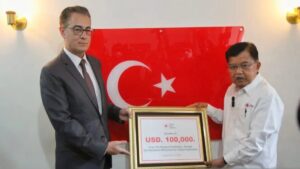 Ketua Umum PMI Jusuf Kalla saat menyerahkan bantuan Duta Besar Turki untuk Indonesia yang diwakili Ömer Orhun Çelikol pada Jumat, (10/2). (Antara/HO/Humas PMI)