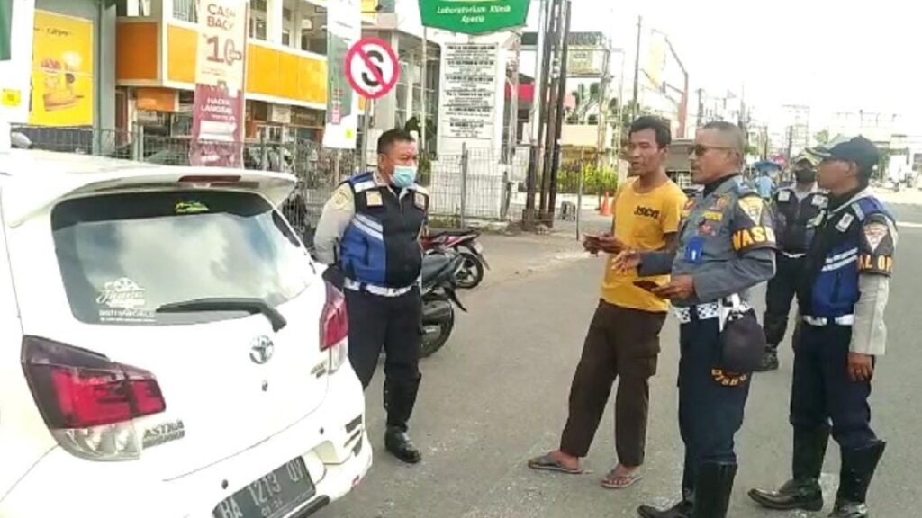Petugas Dishub Kota Padang memberi imbauan kepada salah seorang tukang parkir yang mengenai badan jalan. (Dok. Dishub Padang)