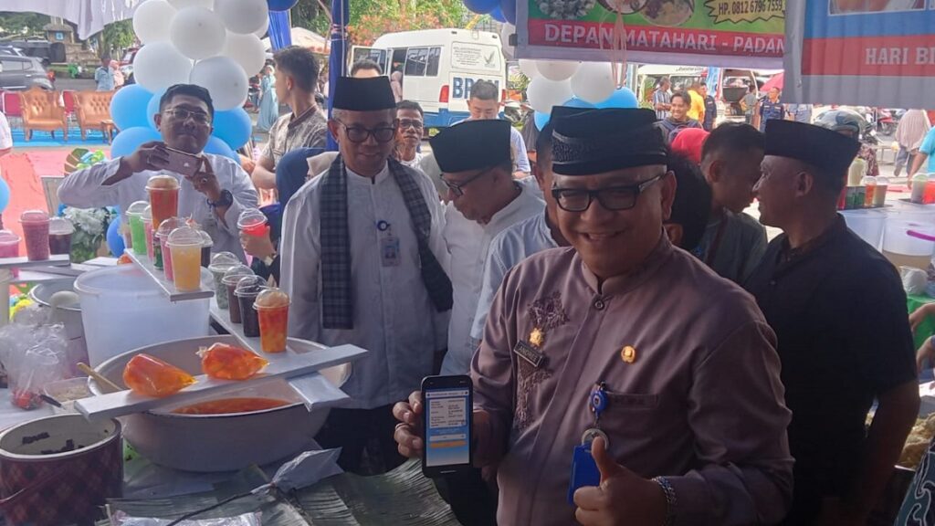 Pedagang Pasa Pabukoan RTH Imam Bonjol menggunakan QRIS untuk metoda pembayaran takjil saat bertransaksi dengan Sekda Kota Padang, Andree Harmadi Algamar. (Foto: Dok. Muhammad Aidil)