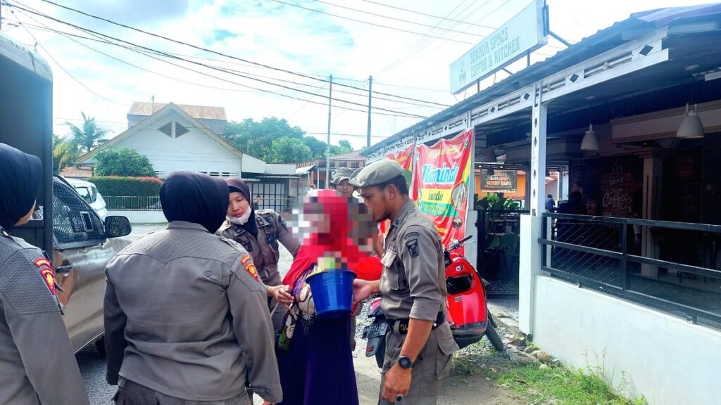 Petugas mengamankan perempuan pengemis yang menggendong bayi di jalan raya. (Foto: Dok. Satpol PP Kota Padang)