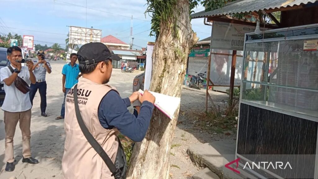 Tim dari Bawaslu Agam sedang membuka baliho yang terpasang di pohon pelindung, Sabtu (27/1/2024). (Dok Antara/Yusrizal)