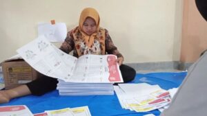 Petugas penyortiran dan pelipatan surat suara di gudang KPU Solok Selatan sedang mencermati lembar surat suara sebelum dilipat. (dok. Antara/Erik)
