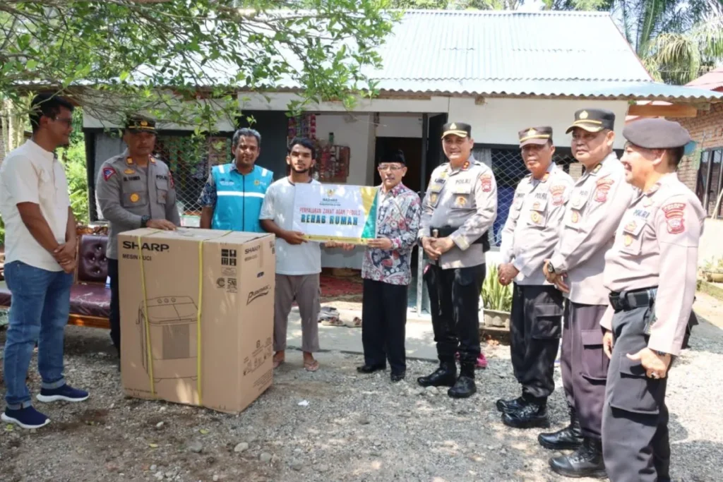 Kapolres Agam, AKBP Muhammad Agus Hidayat mendampingi Ketua Baznas Agam Isman Imran menyerahkan bantuan renovasi rumah untuk Firman Darma. (Foto: Dok HO/Humas Polres Agam)