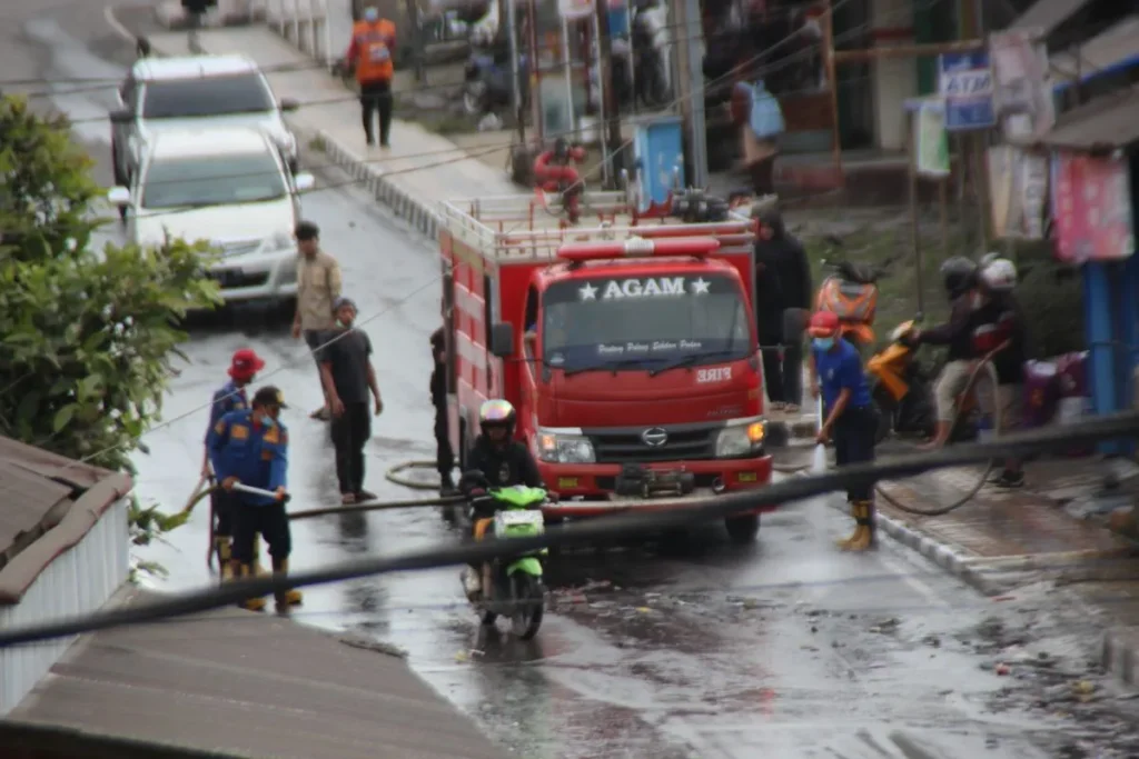 Petugas pemadam kebakaran (Damkar) menyiram jalanan di Kabupaten Agam yang dipenuhi kabut abu vulkanik akibat terjadinya erupsi Gunung Marapi.(Foto: Dok. Antara/Al Fatah)