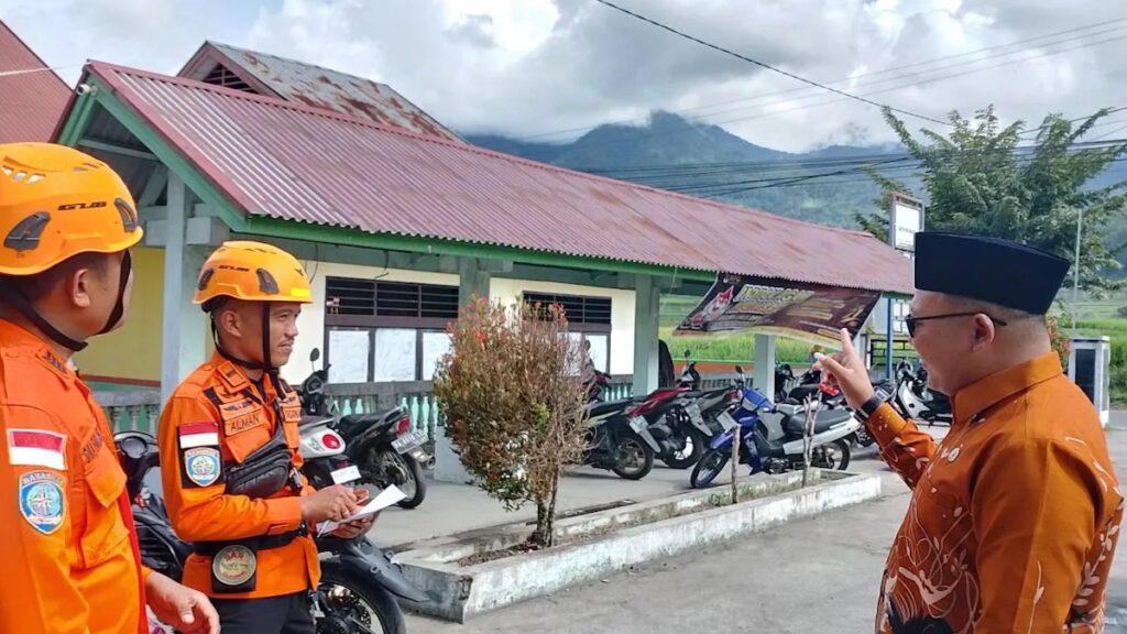 Kepala Desa Bukik Batabuah, Firdaus bersama petugas Basarnas dengan latar belakang Gunung Marapi tertutup awan. Sebanyak 1.300 jiwa di sekitar puncak Gunung Marapi masih beraktivitas normal hingga saat ini.(Antara/Al Fatah)