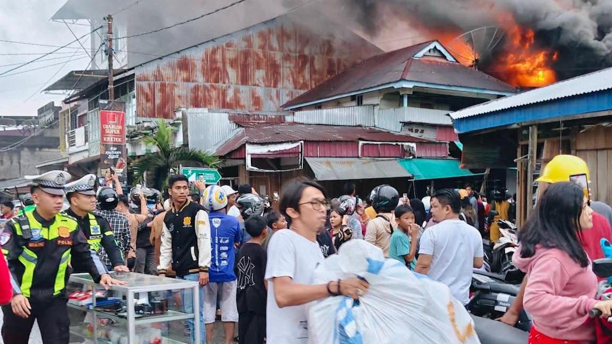 Para pedagang korban kebakaran 17 unit rumah toko (ruko) di Lingkungan I, Kelurahan Pasar, Kota Gunungsitoli, Sumut berupaya menyelamatkan barang di tengah kobaran api, Kamis (10/4/2026) sore. (Putra/Radar Sumbar).